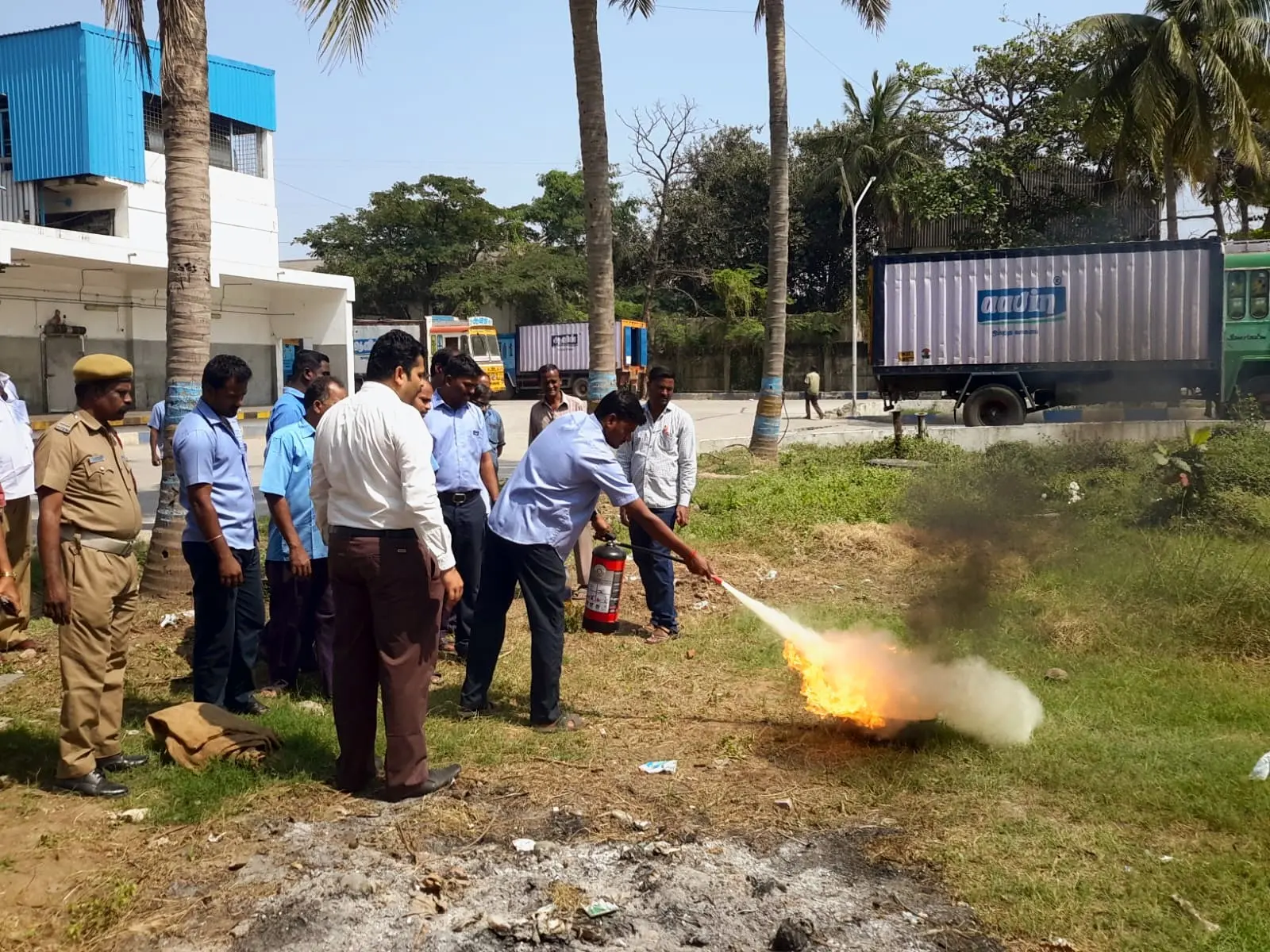 A plant worker puts out a test fire, a fire officer looking on
