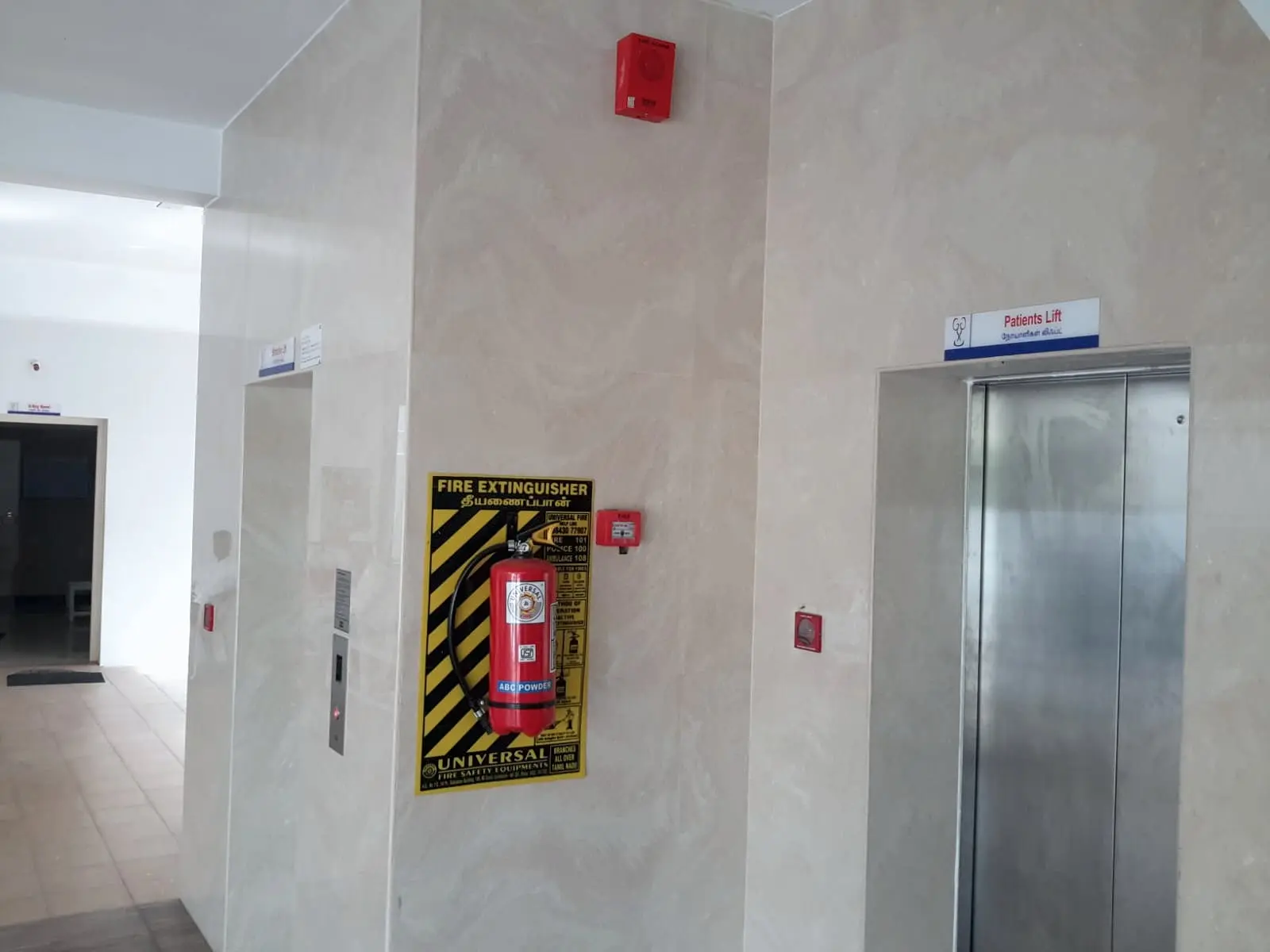 Extinguisher, hooter and call points in a hospital lift lobby