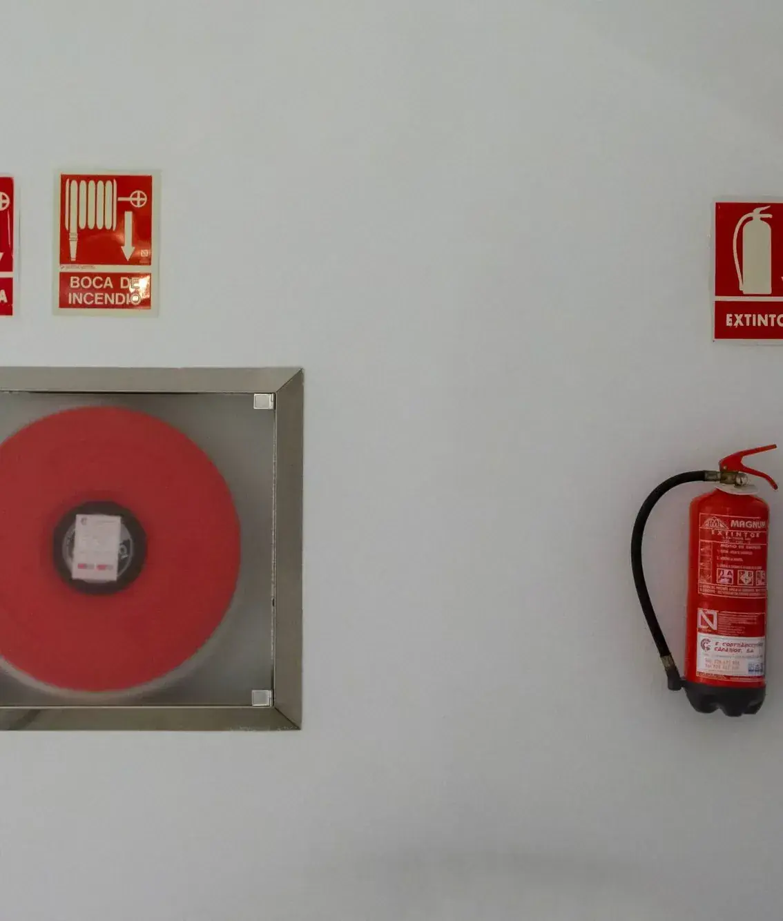 Hose reel cabinet and fire extinguisher on a commercial building wall