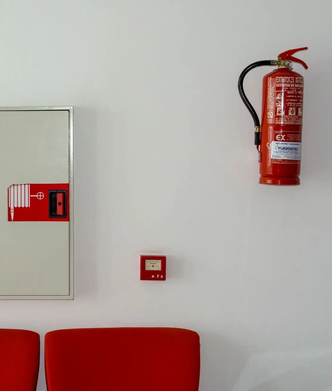 Fire extinguisher, hose cabinet and alarm call point above public seating