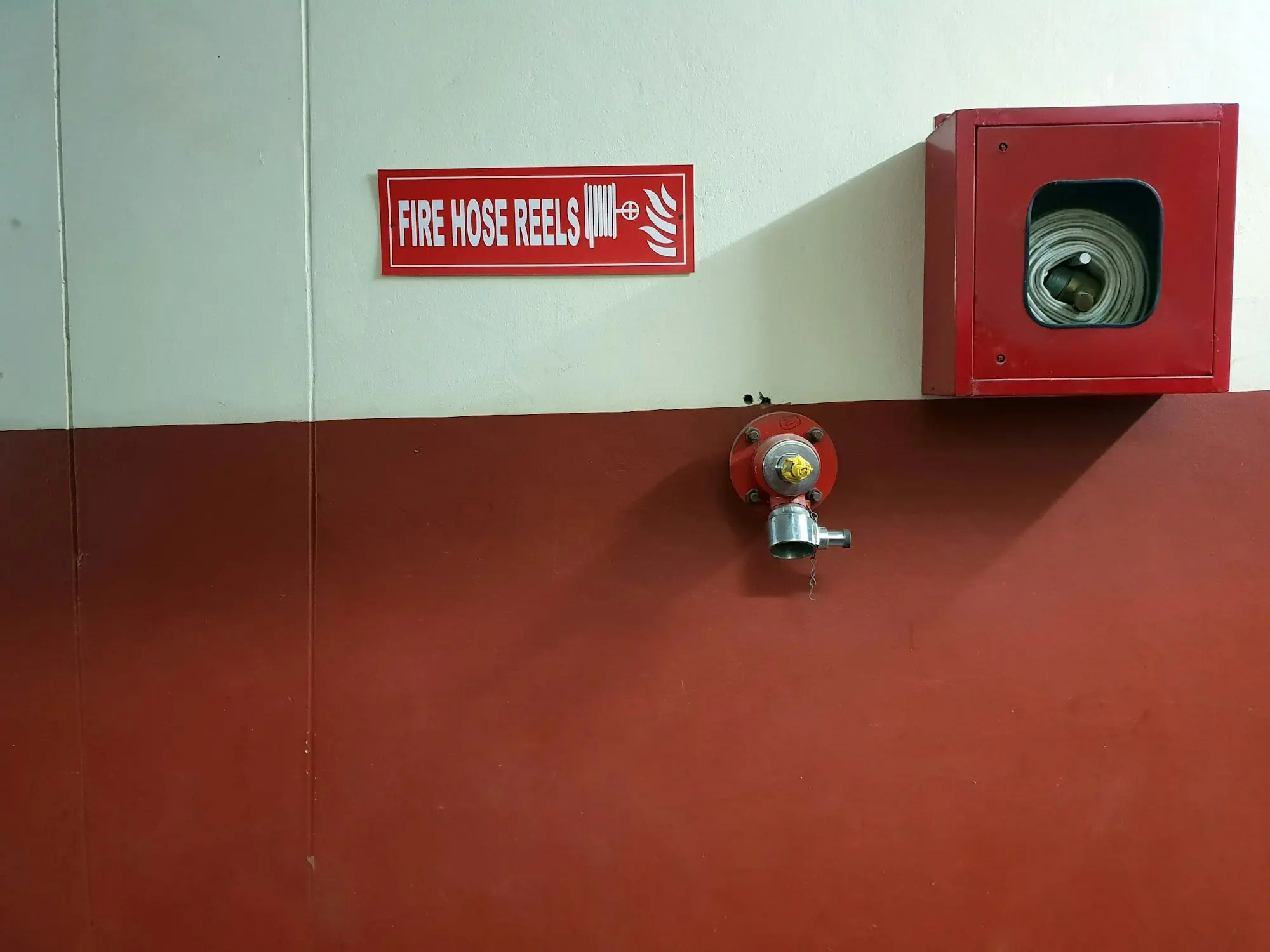 Fire hose reel cabinet and landing valve on a red wall