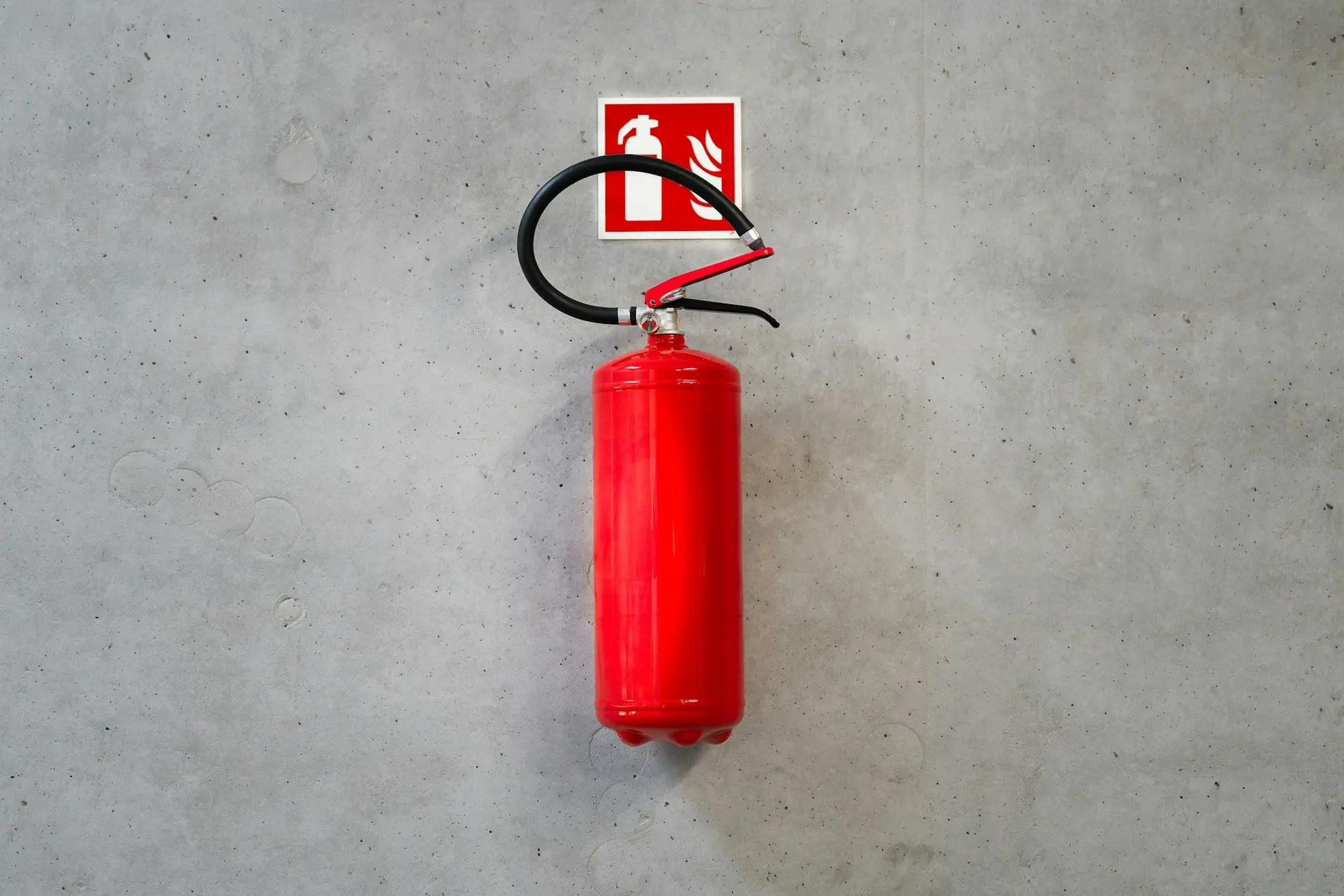 Fire extinguisher under its sign on a concrete wall